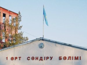 Fire station building in Konaev, Kazakhstan with the national flag on pole against a blue sky.